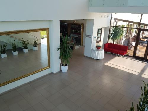 a lobby with a red chair and potted plants at Rezidencija Grįžulo ratai in Sasnava