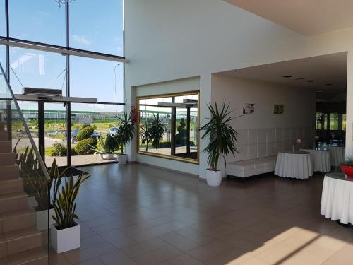 a lobby with tables and plants in a building at Rezidencija Grįžulo ratai in Sasnava
