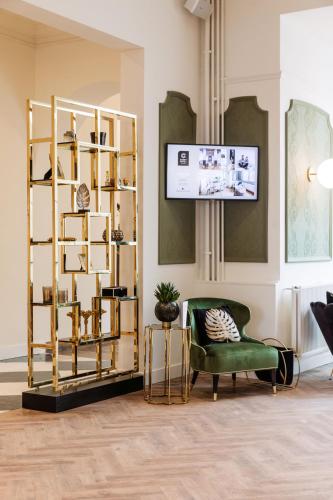 a living room with a green chair and a shelf at C-Hotels Continental in De Panne