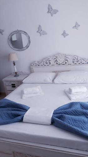 a white bed with a blue blanket and a mirror at Christos Rooms in Palaiochóra