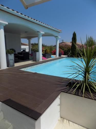 une piscine avec une terrasse en bois à côté d'une maison dans l'établissement Villa VAYA, à Villemoustaussou