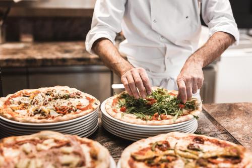 a chef preparing three pizzas on plates on a counter at Anthony's Life&Style Hotel in Sankt Anton am Arlberg