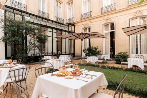 a restaurant with white tables and chairs in front of a building at Hôtel Alfred Sommier in Paris
