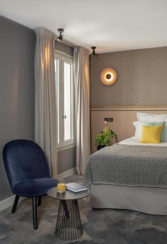 une chambre avec un lit et une chaise bleue dans l'établissement Hotel Opéra Marigny, à Paris