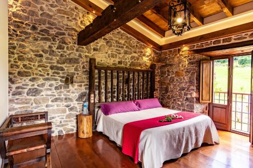1 dormitorio con 1 cama en una pared de piedra en Casona de El Castañíu, en Serrapio