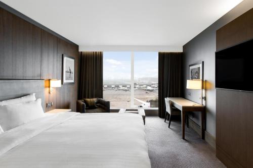 a hotel room with a large bed and a desk at Radisson Blu Manchester Airport in Hale