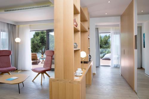 a living room with wooden shelves and chairs and a table at Dolce by Wyndham Athens Attica Riviera in Vravrona