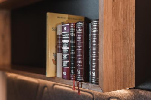 a row of books sitting on a book shelf at Anthony's Life&Style Hotel in Sankt Anton am Arlberg