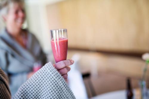 a hand holding a glass with a pink drink at Stiftsgården Åkersberg in Höör