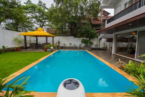 a swimming pool in the backyard of a house at EL Lodge by StayVista - Pool, lawn, and a charming gazebo for your perfect getaway in Lonavala