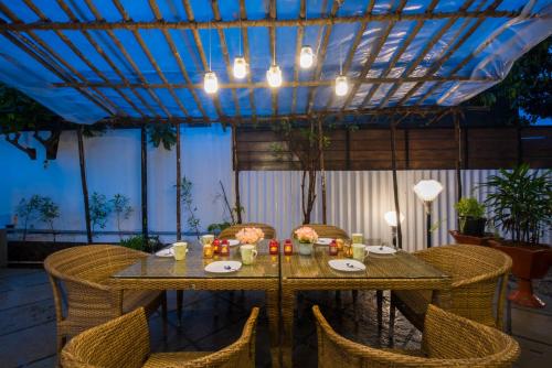 a dining table with wicker chairs and a blue ceiling at EL Lodge by StayVista - Pool, lawn, and a charming gazebo for your perfect getaway in Lonavala