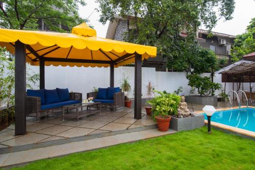 a patio with a yellow umbrella and a pool at EL Lodge by StayVista - Pool, lawn, and a charming gazebo for your perfect getaway in Lonavala