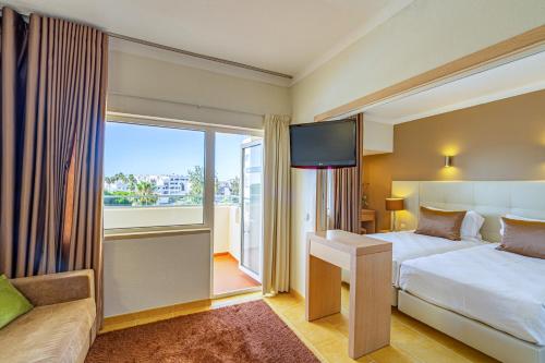アルブフェイラにあるAlbufeira Sol Hotel & Spaのベッドと大きな窓が備わるホテルルームです。