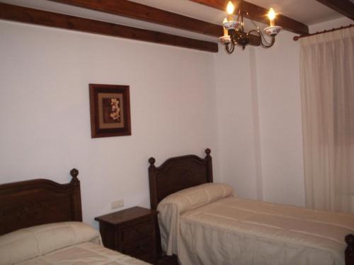 a bedroom with two beds and a chandelier at Casa Rural Arturo I in Sahagún