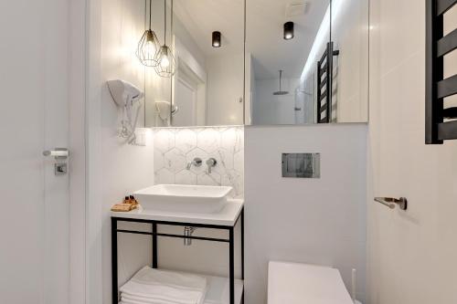 a white bathroom with a sink and a mirror at Pogodna Apartments in Sopot