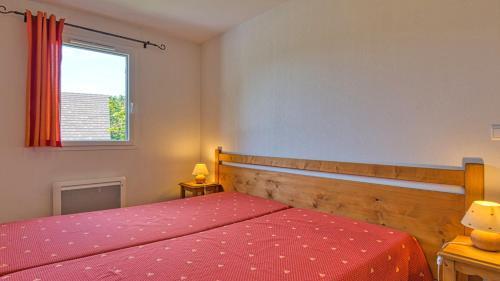a bedroom with a bed with a red bedspread and a window at Vacancéole - Residence le Domaine du Bosquet in Égletons