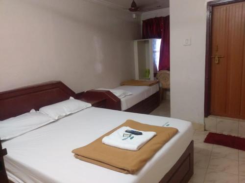 a bedroom with two beds with a towel on them at Anandan Tourist Home in Varkala