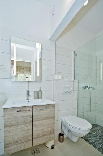 a white bathroom with a toilet and a sink at Apartments Magdalena in Hvar