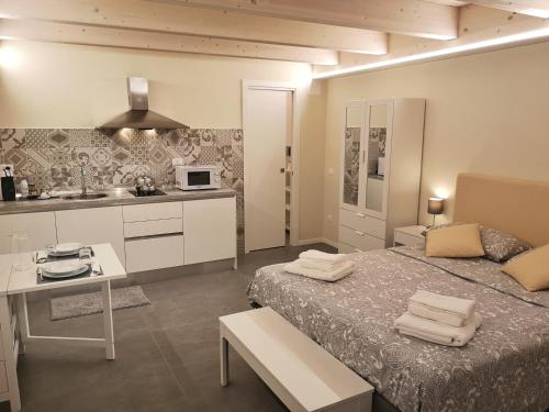グアルディアグレーレにあるVico-Letto studio apartmentのベッド、デスク、キッチンが備わる客室です。