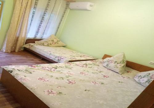 two beds in a small room with flowers on them at Guest House U Aidy in Novy Afon