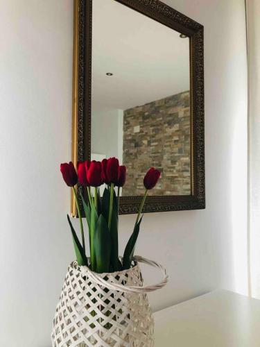 Eine Vase mit roten Tulpen vor einem Spiegel in der Unterkunft Duplex Archidona Centro in Archidona