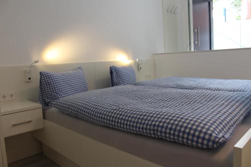 Schlafzimmer mit einem Bett mit blauer und weißer Bettwäsche und einem Fenster in der Unterkunft Haus Etzold in Norderney