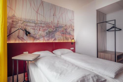 a bed in a room with a painting on the wall at Campanile Berlin Brandenburg Airport in Schönefeld