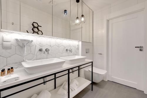 a white bathroom with two sinks and a toilet at Pogodna Apartments in Sopot