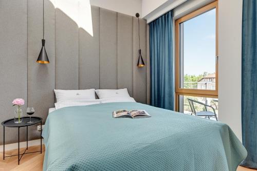 a bedroom with a bed with a book on it at Pogodna Apartments in Sopot