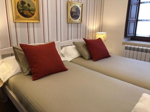 2 camas con almohadas rojas y blancas en una habitación en El Cuartel del Rio Dulce, en Mandayona