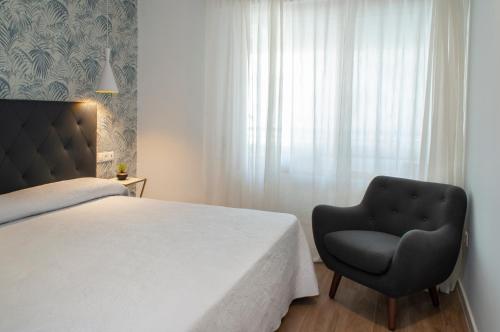 een slaapkamer met een bed en een stoel naast een raam bij Stay In Plaza in Alicante