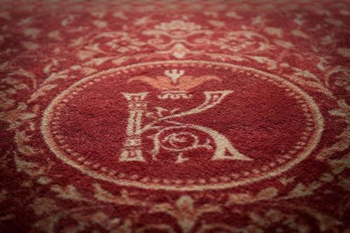 a red rug with a letter k on it at Deluxe Hotel Kupava in Lviv