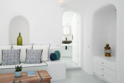 a white living room with a couch and a table at Oia Spirit Boutique Residences in Oia
