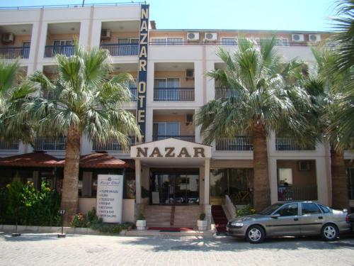 a car parked in front of a hotel with palm trees at Nazar Hotel in Didim