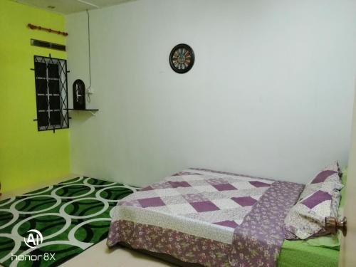 a bedroom with a bed and a clock on the wall at BB HOMESTAY in Kampung Tualang