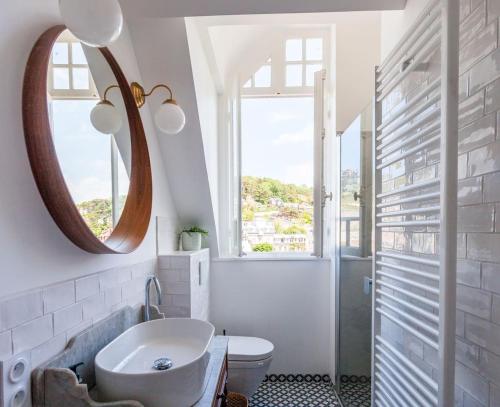 une salle de bain avec un lavabo, des toilettes et un miroir dans l'établissement Greeter-Bel appartement au pied des falaises d'Etretat, à Étretat