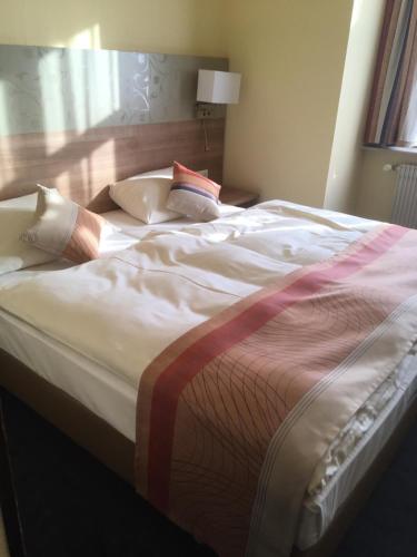 a large bed with white sheets and pillows on it at Hotel Hechinger-Hof in Hechingen