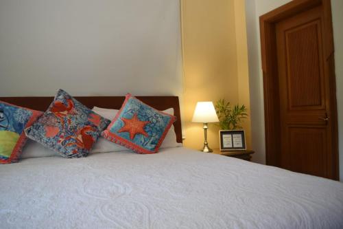a bedroom with a bed with pillows and a lamp at Porto Bello Hotel Boutique in Puerto Colombia