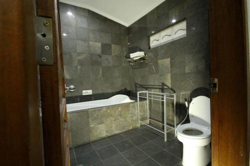 La salle de bains est pourvue de toilettes et d'une baignoire. dans l'établissement Swastika Guesthouse Sanur, à anur