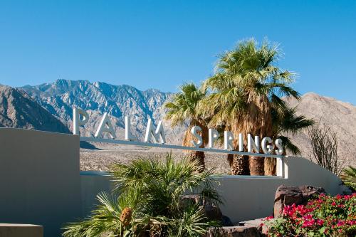 a sign for a hotel with palm trees and mountains at Sordid Lives Condo Permit# 3202 in Palm Springs