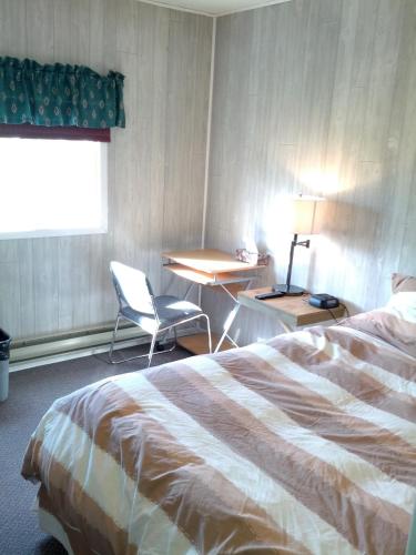 Habitación de hotel con cama, escritorio y ventana en Bear Country Inn, en Churchill