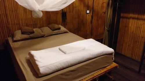 a bed in a room with white sheets at Seacroft Bamboo Village in Hinkong