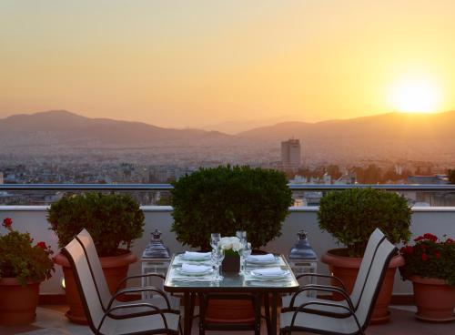 a table and chairs on a balcony with the sunset at Athens Zafolia Hotel in Athens