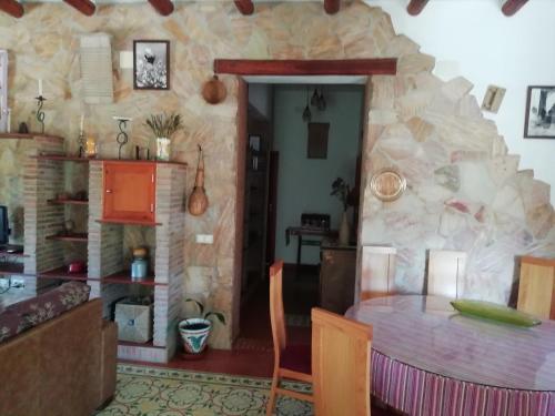 ein Esszimmer mit einem Tisch und einer Steinmauer in der Unterkunft Alojamiento Rural La Perdiz in La Puebla de los Infantes
