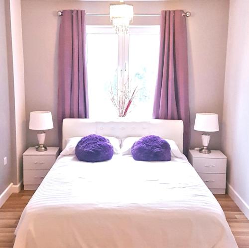 - une chambre avec un lit doté d'oreillers violets et d'une fenêtre dans l'établissement 3 Bed Luxury Town Center Apartment with 50 inch 4K TV (Netflix & NowTV Ent. Pass), à Northampton