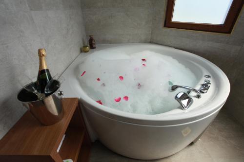 a bath tub with a bottle of champagne next to it at Provence rooms in Banja Luka