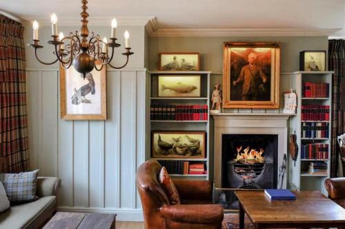 a living room with a fireplace and a chandelier at The Loch Lomond Arms Hotel in Luss