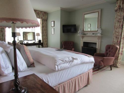 a bedroom with a large white bed and a mirror at The Loch Lomond Arms Hotel in Luss