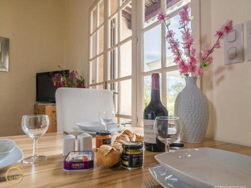 a table with a bottle of wine and a vase with flowers at Les Garrigues de la Vallée des Baux in Paradou