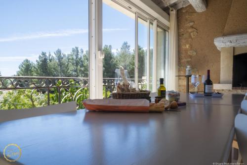 a kitchen with a table with a view of a balcony at Les Garrigues de la Vallée des Baux in Paradou